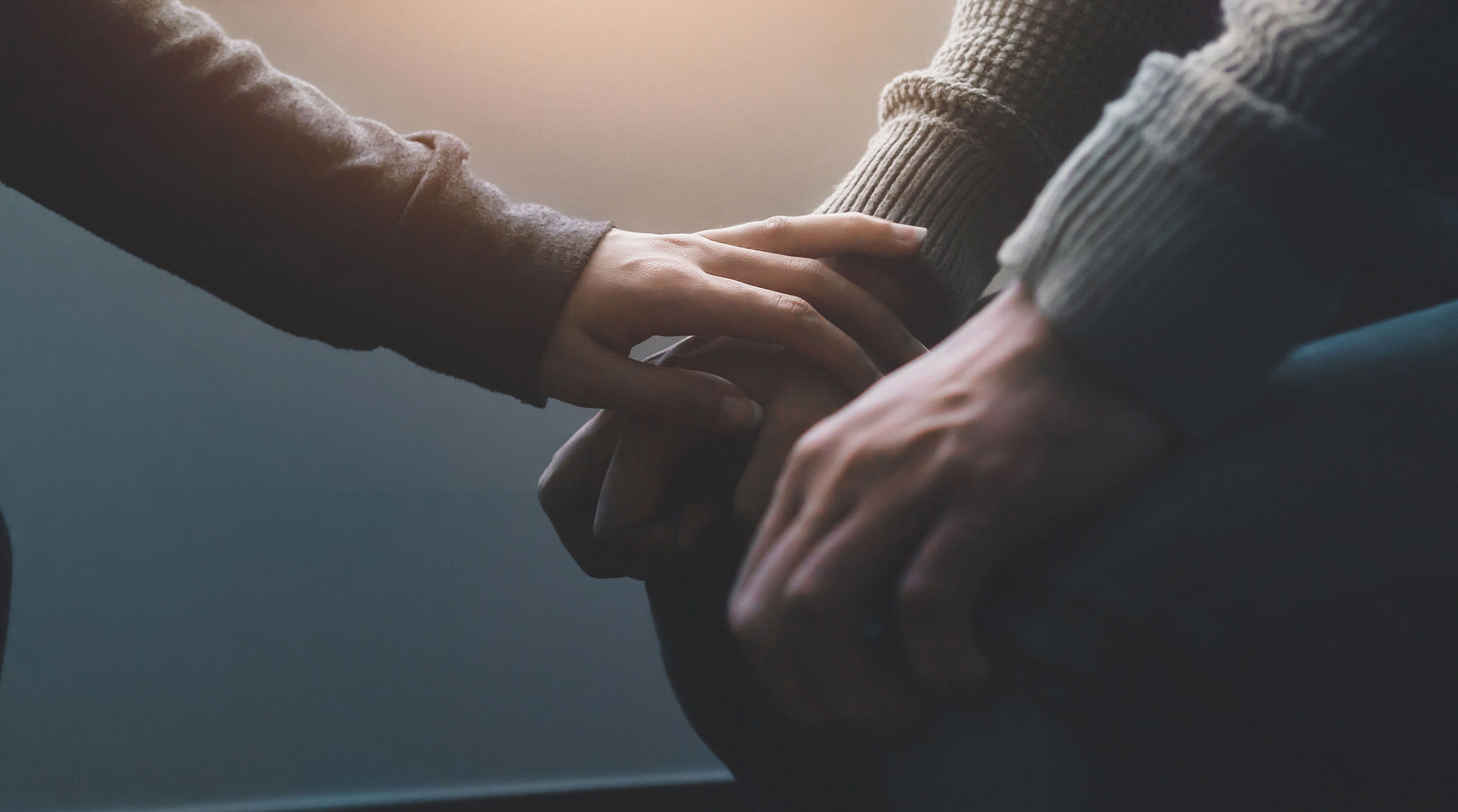 Close up of one friend comforting another showing arms and hands only.