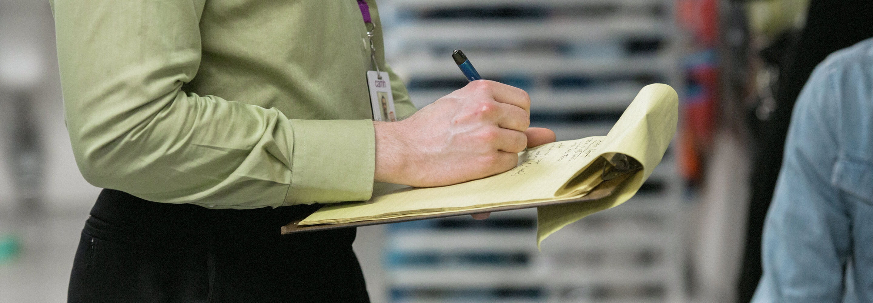A woman  writes on a clipboard.