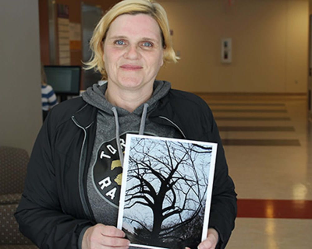 CAMH client Christine holds photograph she took that was selected for photo exhibit
