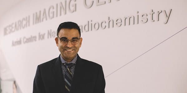A man of colour standing in front of the Azrieli Centre for Neuro-Radiochemistry