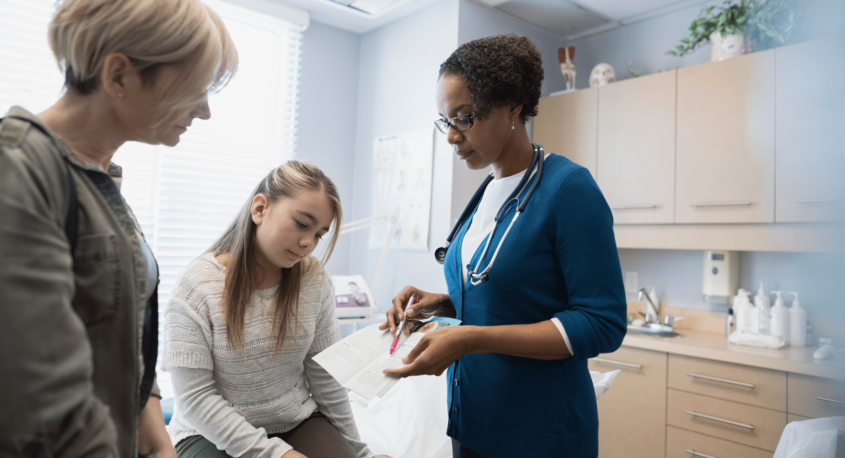 mother and daughter look at information pamphlet with medical professional
