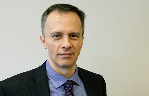 Dr. Jeffrey Meyer in a black blazer and blue dress shirt with a dark blue-polka dot tie smiling. 