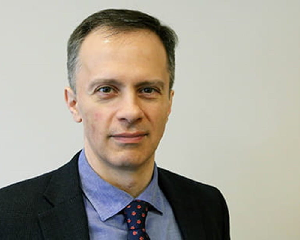 Dr. Jeffrey Meyer in a black blazer and blue dress shirt with a dark blue-polka dot tie smiling. 