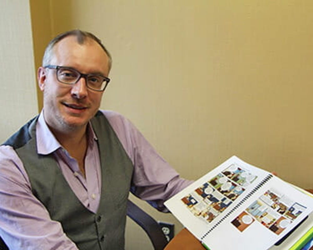 A man with glasses showing the camera book. 