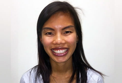 A medium closeup shot of an Asian woman with black hair smiling at the camera. 