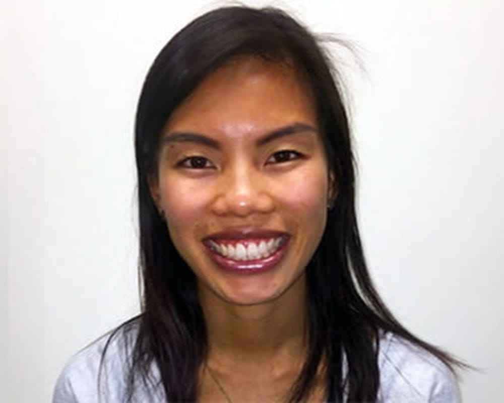 A medium closeup shot of an Asian woman with black hair smiling at the camera. 