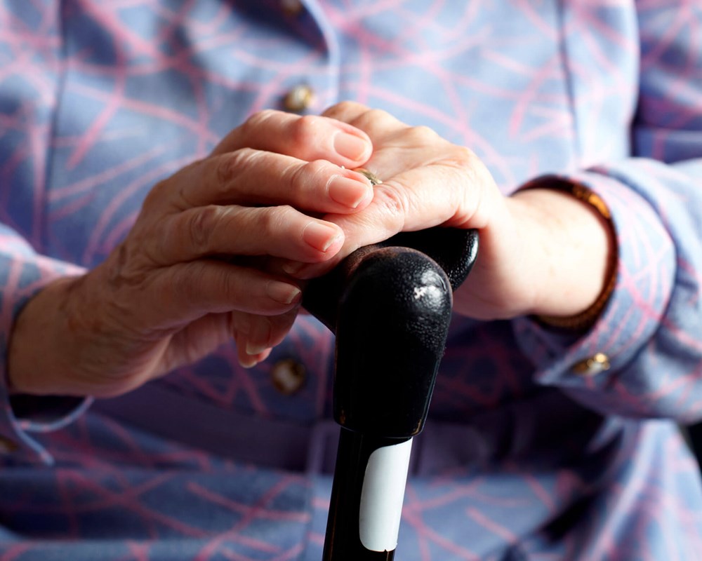 Closeup of hands of elderly woman holding cane.