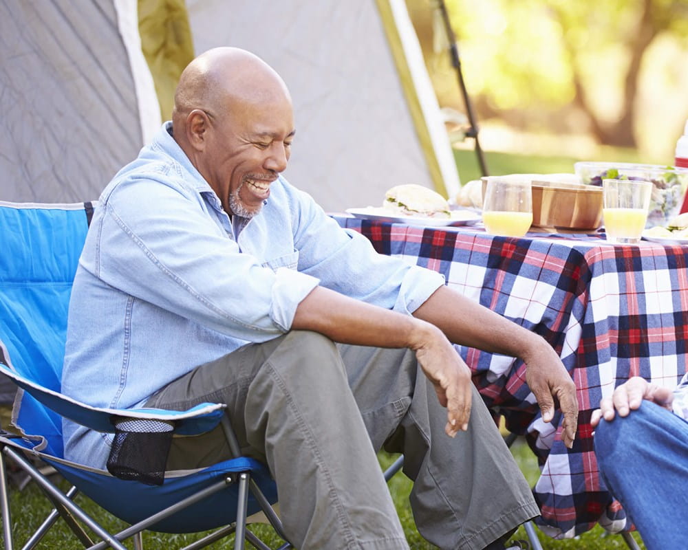 Two older men laughing and talking at a campsite