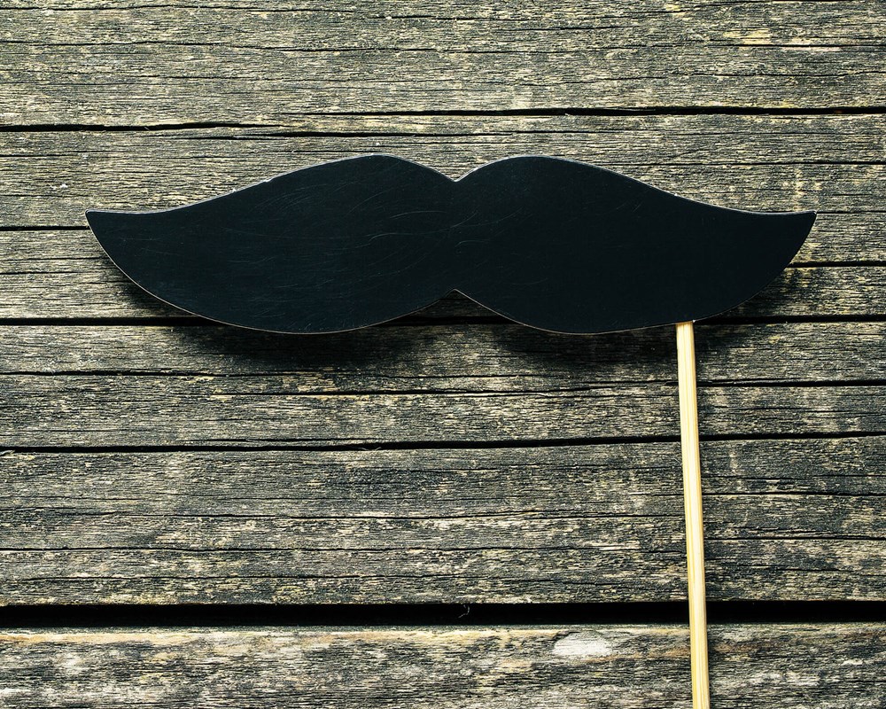 Fake moustache on wood background