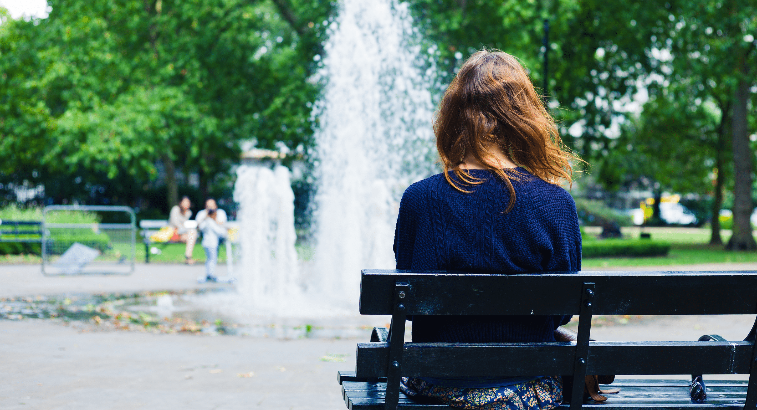 young woman sitting on bench facing away