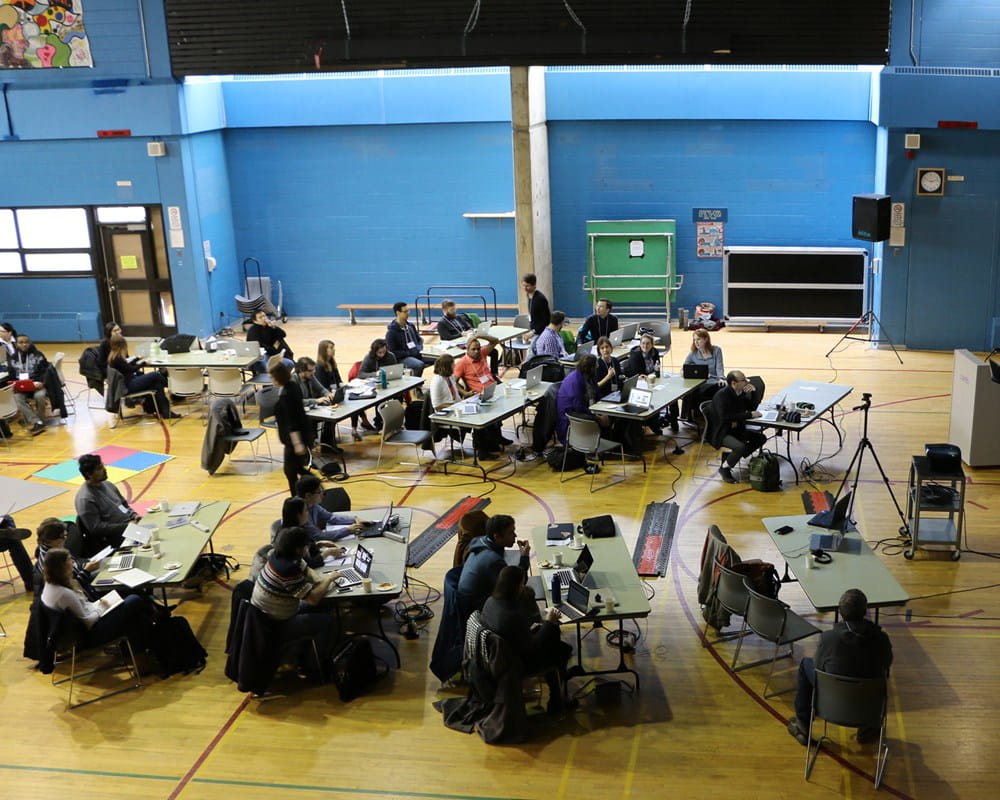 Conference attendees sitting in gymnasium while taking part in CAMH's BrainHack Toronto event