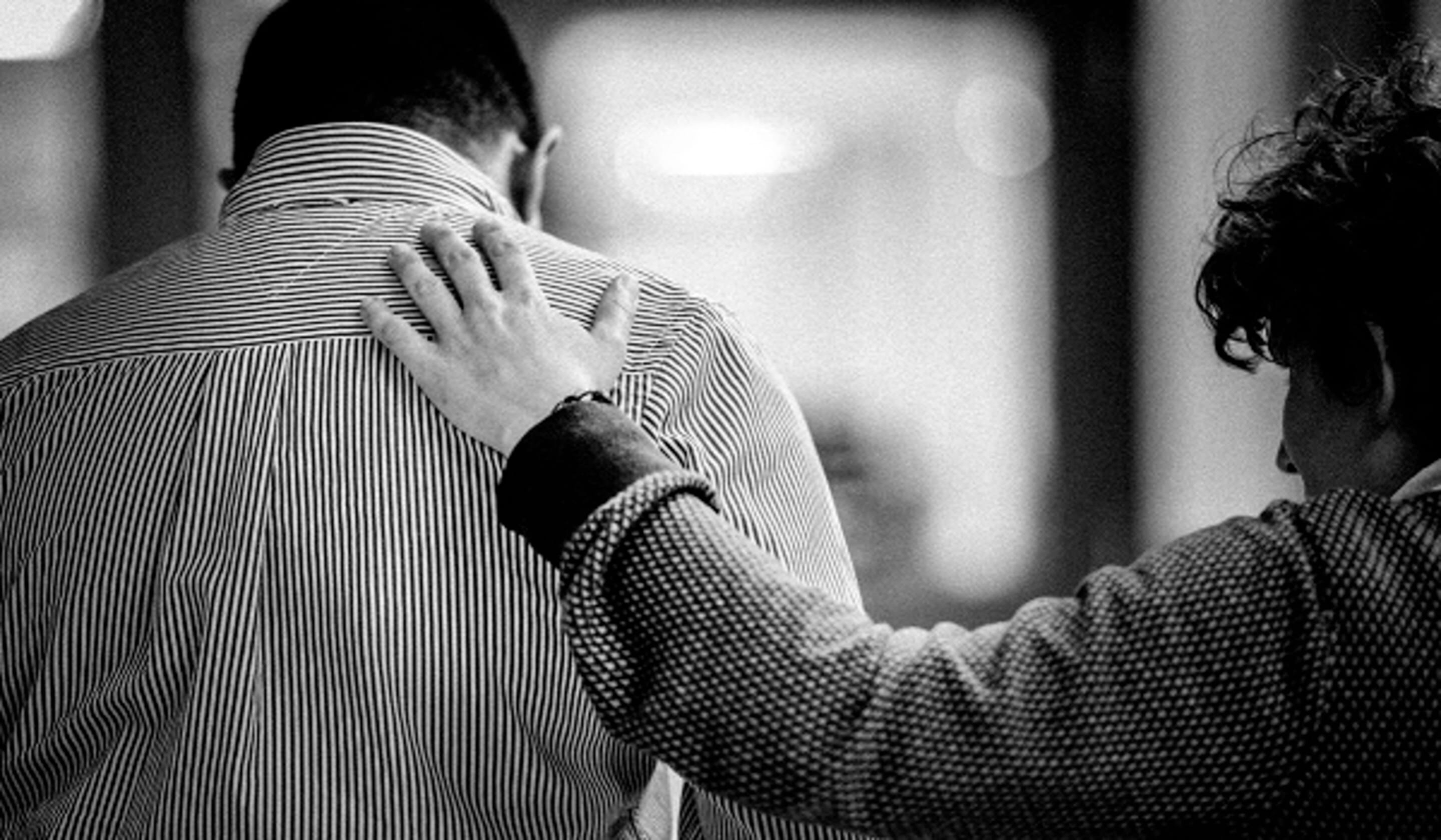 Woman putting her hand on the back of person in distress