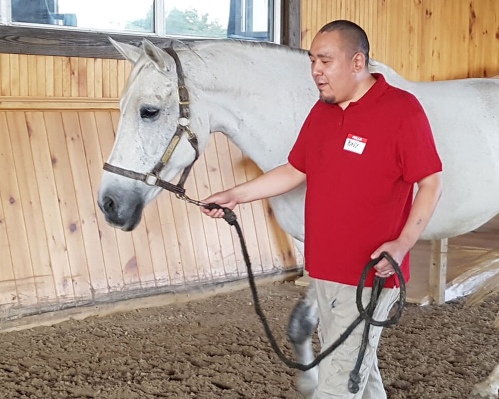 Tony walks horse around indoor arena