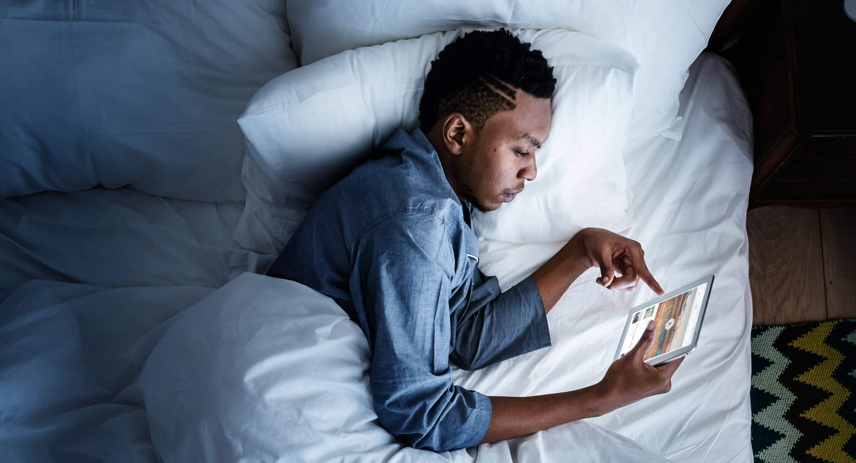 Man in bed holding a digital device
