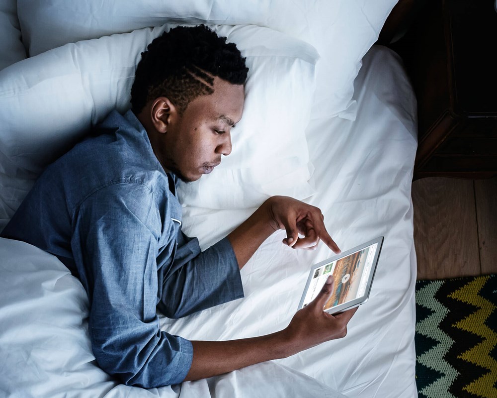 Man in bed holding a digital device