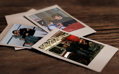 Three polaroid pictures laying on a wooden table. 