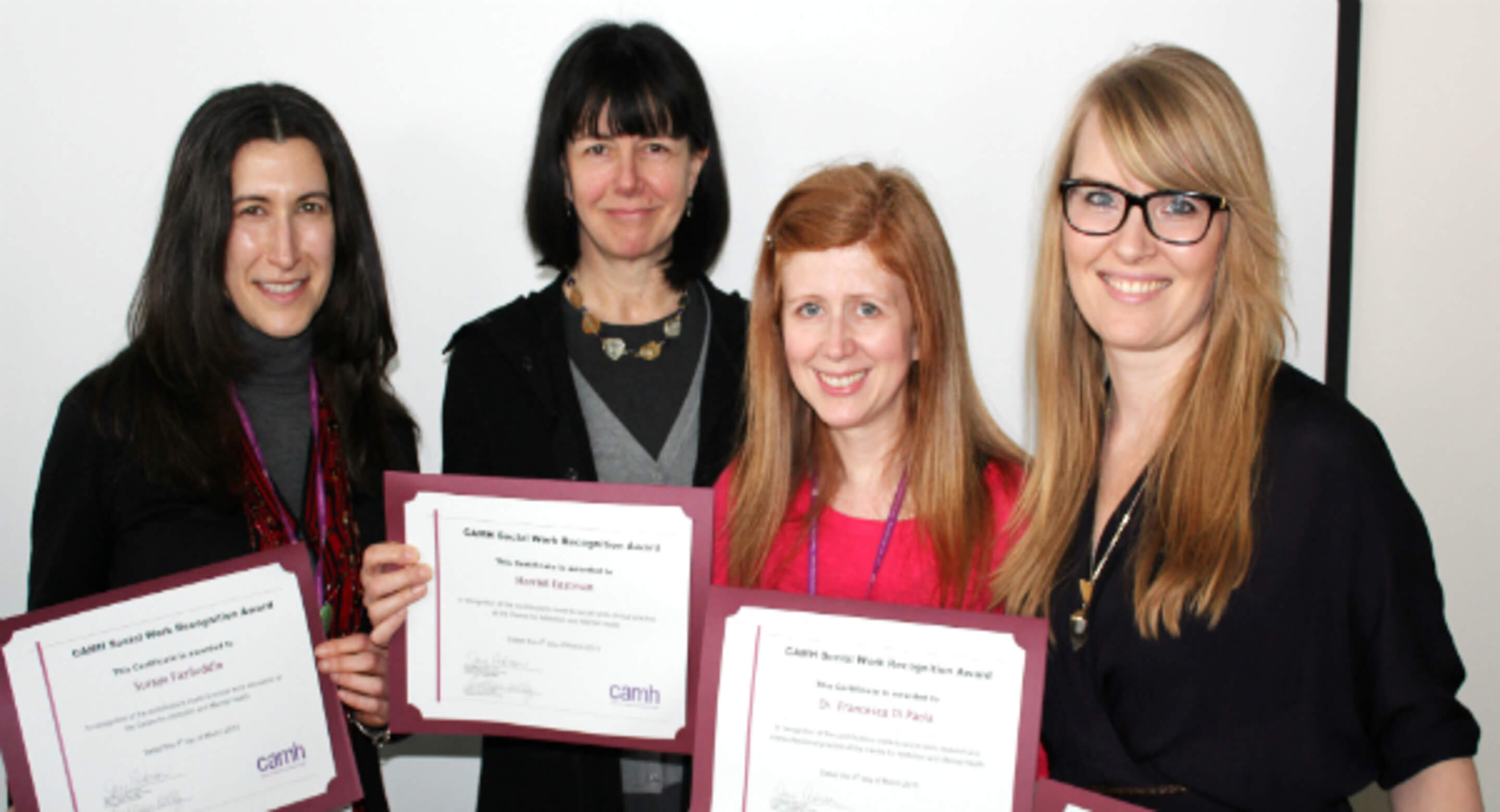 Four women smiling and holding a Social Work Recognition Award in front of their chest. 