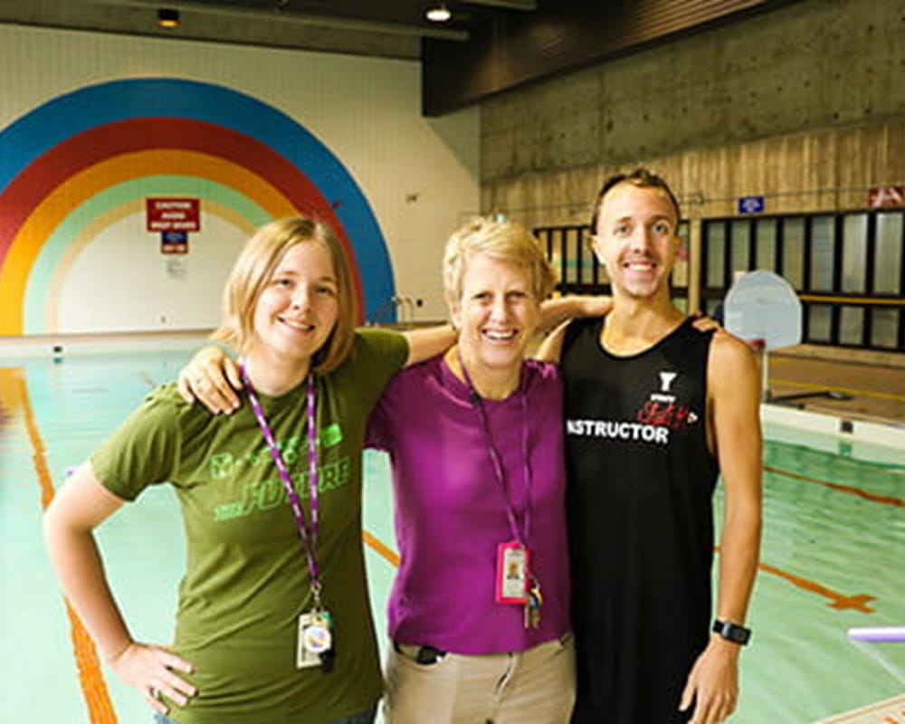 3 CAMH Lifeguards standing in front of a pool.