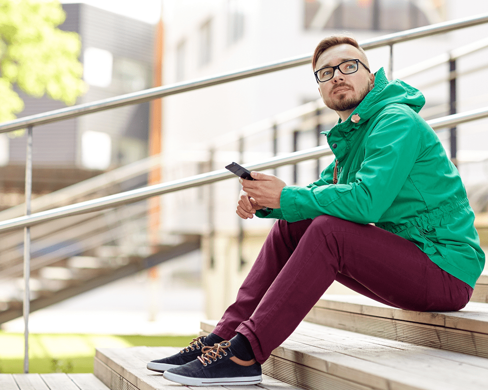young man sitting on steps using smartphone