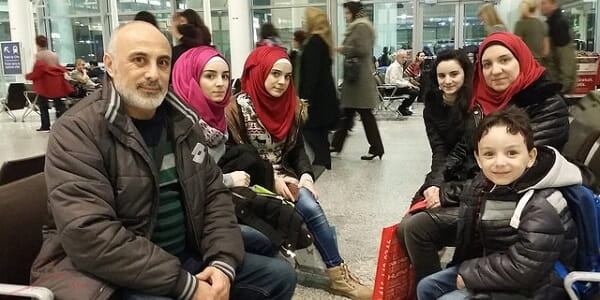 A Syrian Refugee family that just landed in Toronto and are posing together for a picture in the airport. 
