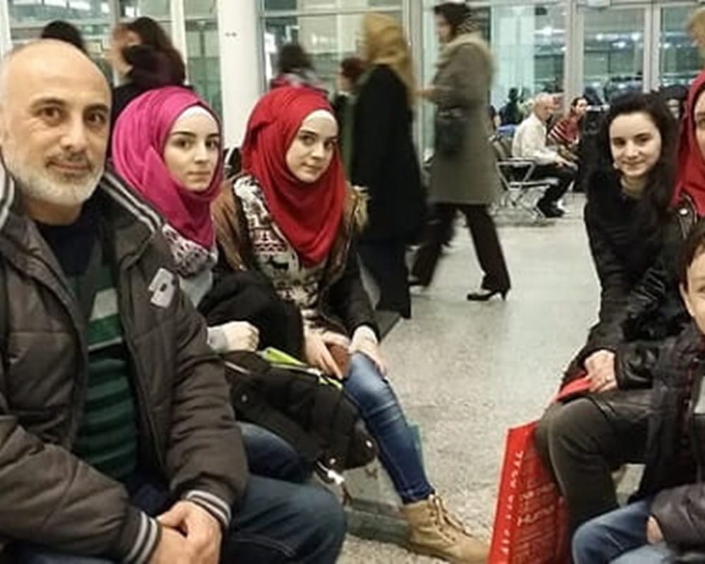 A Syrian Refugee family that just landed in Toronto and are posing together for a picture in the airport. 