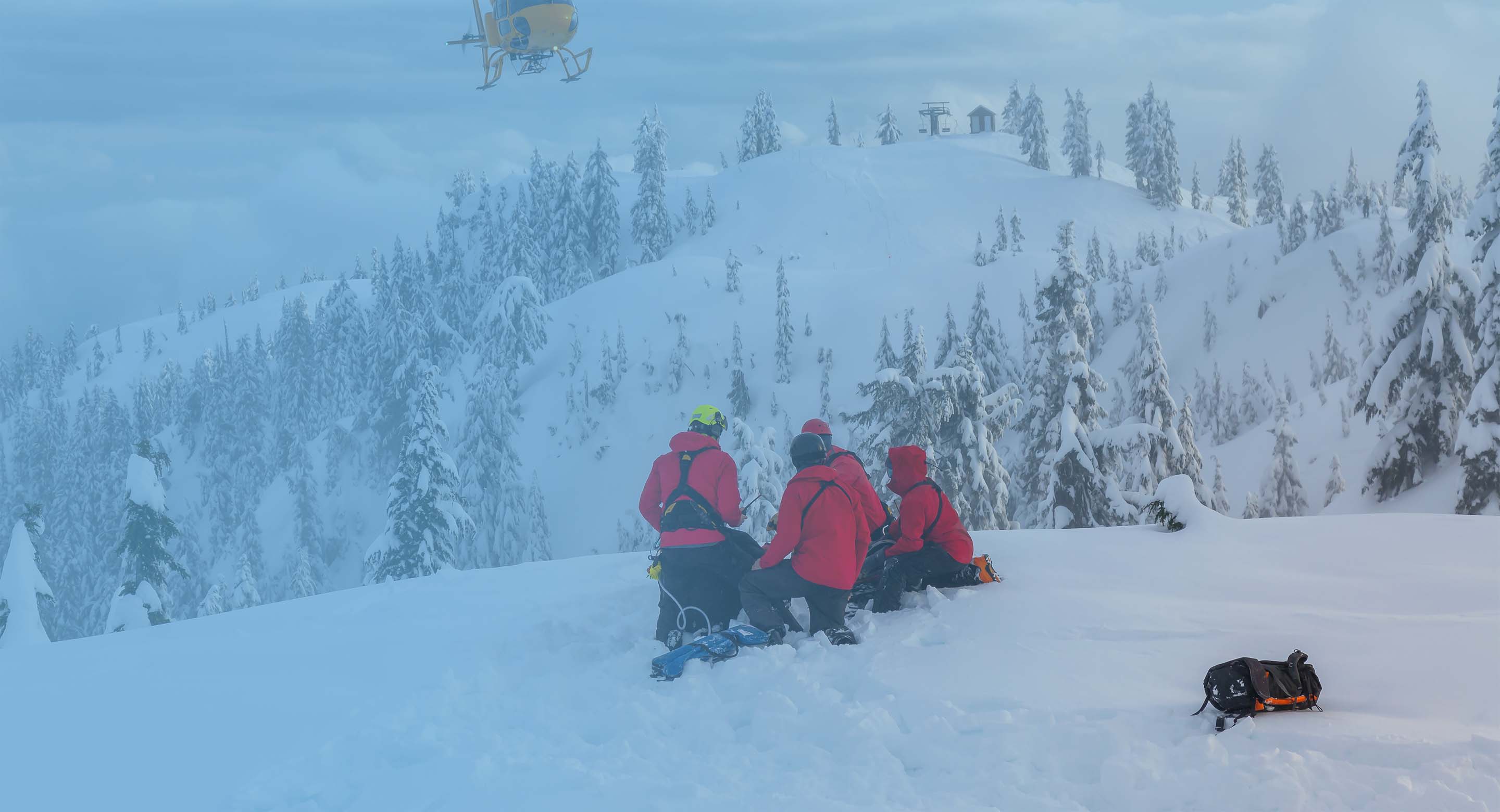 A helicopter flying in to rescue people on a snowy mountain