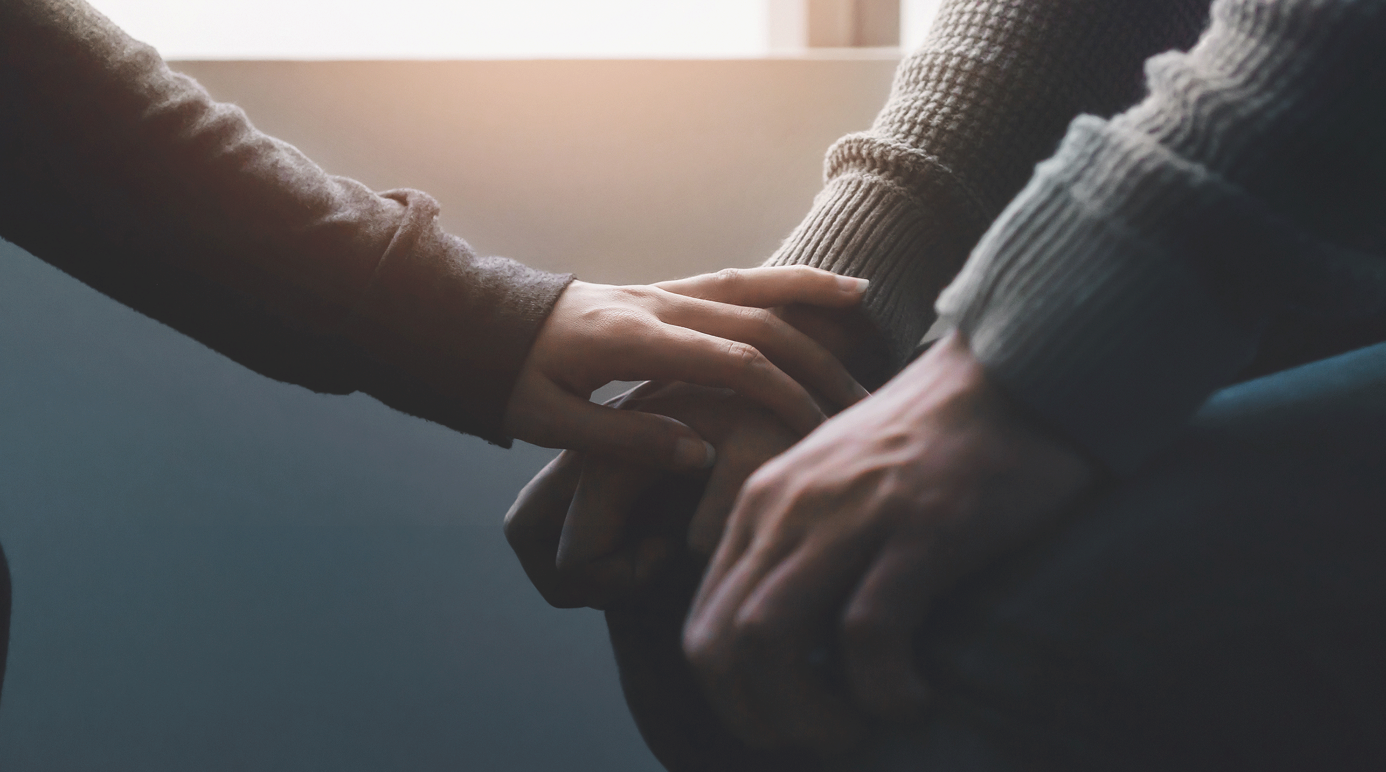 Close up of friend consolling someone, placing their hand on theirs.