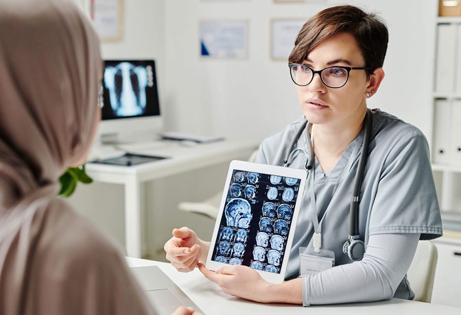Photo of a radiologist showing brain images to a patient on a tablet