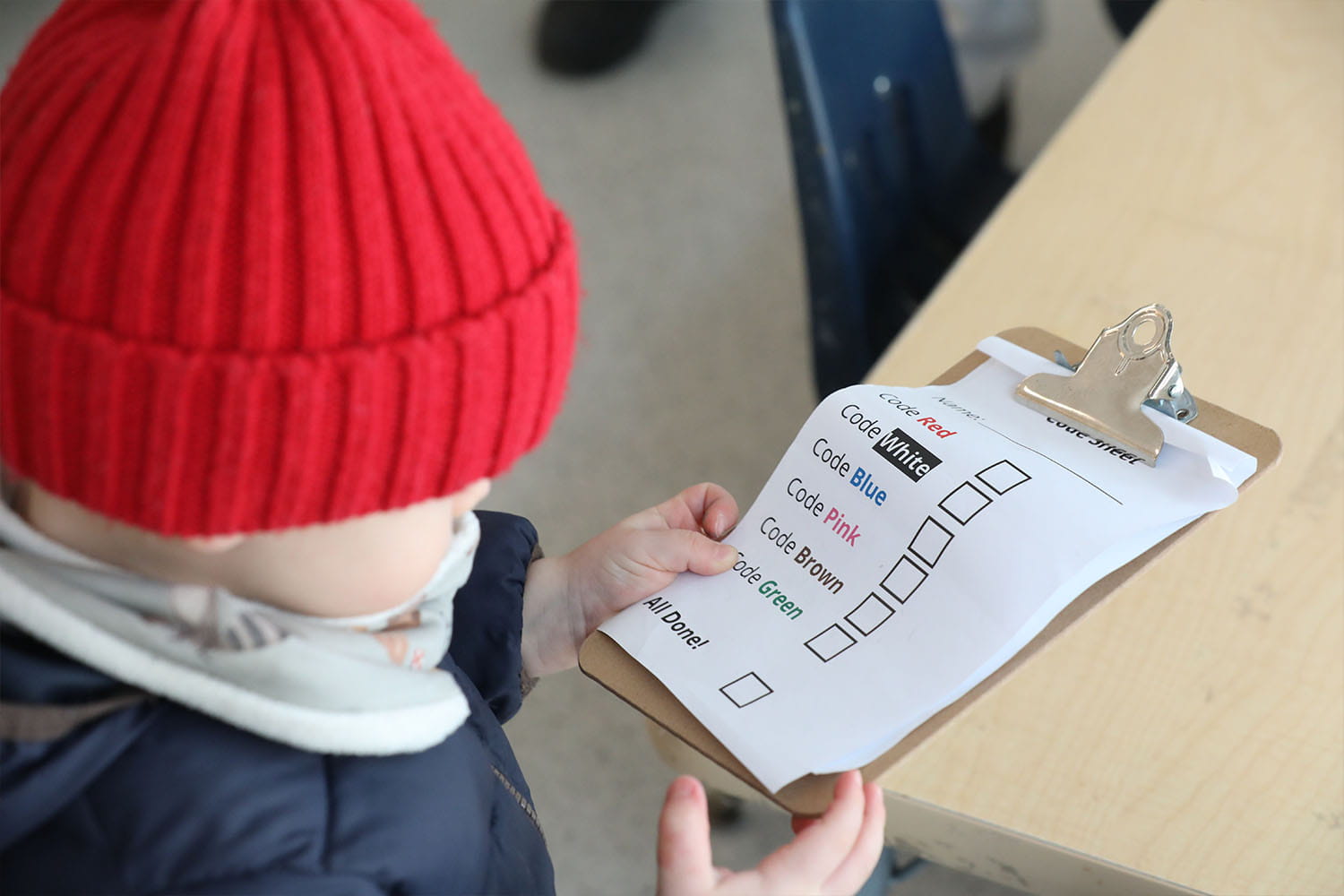 Child looks at a mini clipboard with various codes written in a checklist