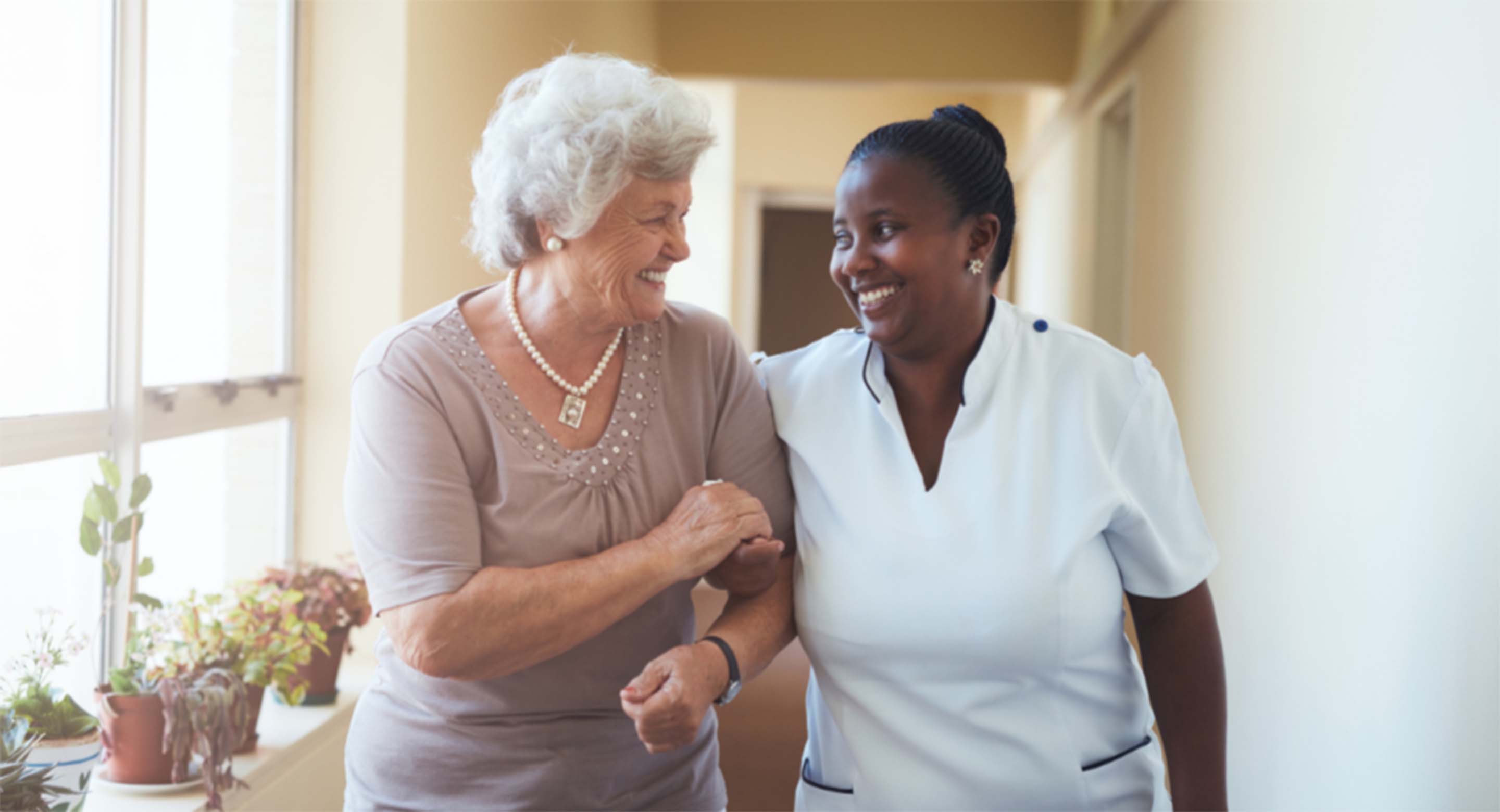 Nurse helping a woman while walking down a hallway
