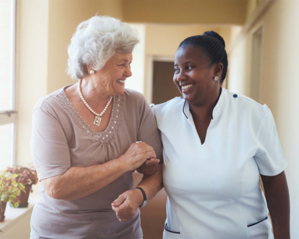 Nurse helping a woman while walking down a hallway