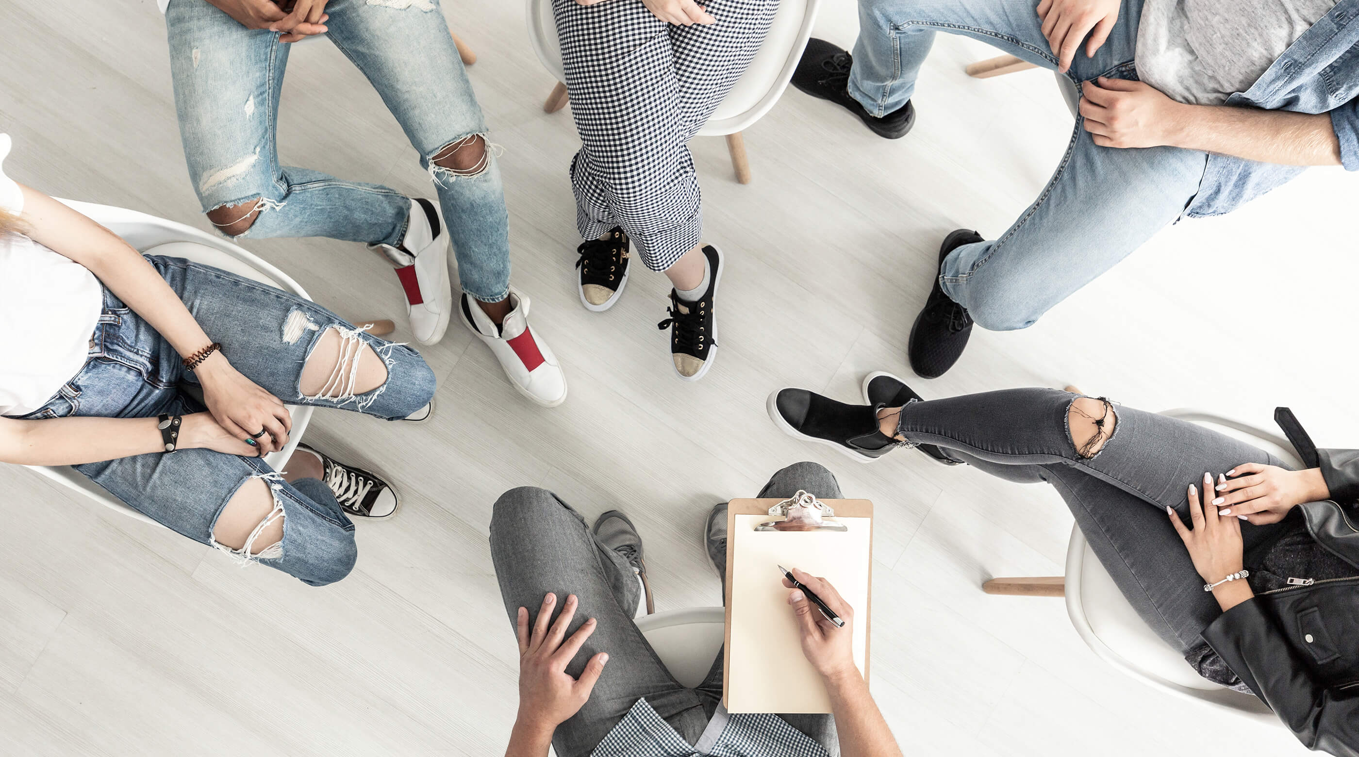 Birds-eye view of a group therapy session with teens and practitioner