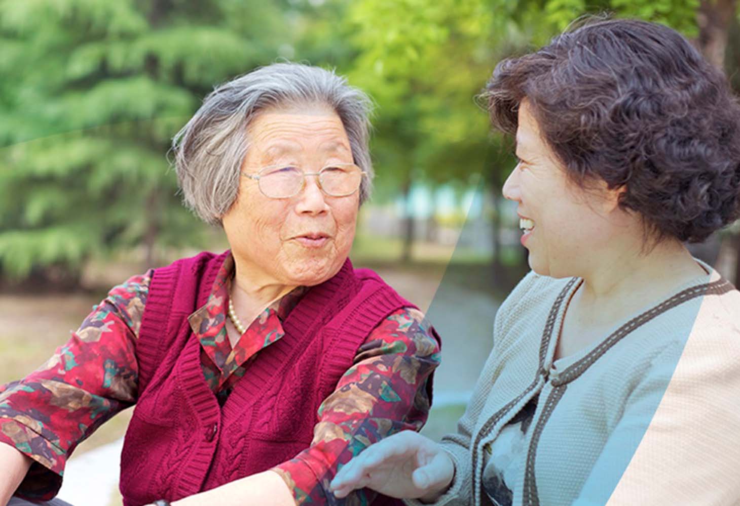 Two older women sitting at a park bench talking